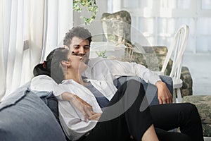 happy couple middle aged man and woman hugging lying relaxing on sofa in modern house living room. happiness man and woman