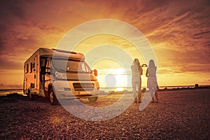 Happy couple with mobile home on the beach photo