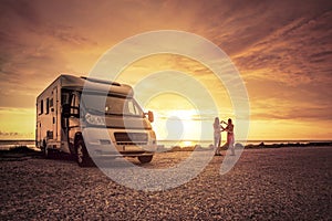 Happy couple with mobile home on the beach photo