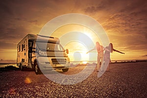 Happy couple with mobile home on the beach photo