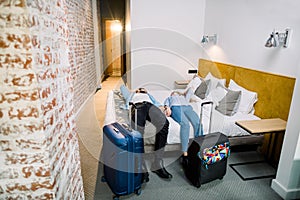 Happy couple in modern hotel room, holidays travel concept. top view of smiling man and woman lying down on the bed