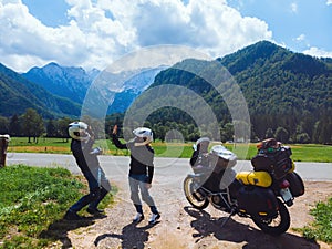 Happy couple of motorcyclists adventure bikers. Green meadow in Zgornje Jezersko, to Kamnik-Savinja Alps on a sunny summer day in