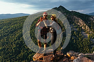 A happy couple in the mountains admires the beautiful views. Travelers enjoy climbing the mountain at sunset