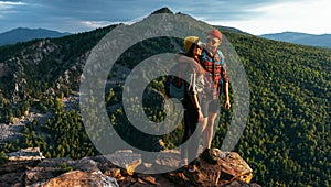 A happy couple in the mountains admires the beautiful views. Travelers enjoy climbing the mountain at sunset