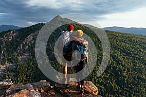 A happy couple in the mountains admires the beautiful views. Travelers enjoy climbing the mountain at sunset