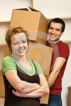 Happy couple moving - carrying boxes