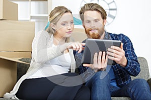 happy couple moving in house using tablet