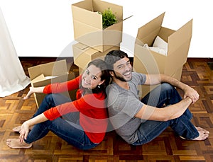 Happy couple moving together in a new house unpacking cardboard boxes