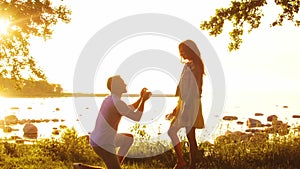 Happy couple near the sea. Field and trees in countryside. Warm colors of sunset or sunrise. Man and woman in love.