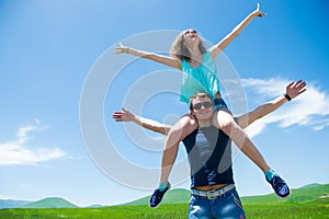 Happy couple with open arms, girl sitting on shoulders man