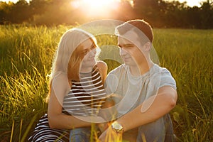 Happy couple outdoor. Smiling couple relaxing on the green grass. Girl and boy over nature green background. Good relationships. R