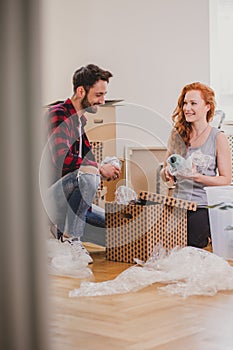 Happy couple packing stuff into a carton box in the interior during relocation