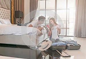 Happy couple packing suitcase on floor in room use tablet for search travel trip online.