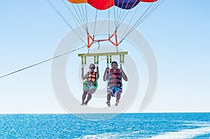 Happy couple Parasailing in Dominicana beach in summer. Couple under parachute hanging mid air. Having fun. Tropical Paradise. Pos photo