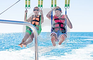 Happy couple Parasailing in Dominicana beach in summer. Couple under parachute hanging mid air. Having fun. Tropical Paradise. Pos photo