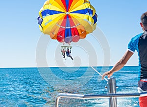 Happy couple Parasailing in Dominicana beach in summer. Couple under parachute hanging mid air. Having fun. Tropical Paradise. Pos