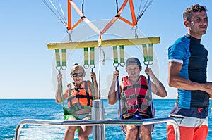 Happy couple Parasailing in Dominicana beach in summer. Couple under parachute hanging mid air. Having fun. Tropical Paradise. Pos