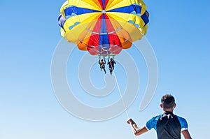 Happy couple Parasailing in Dominicana beach in summer. Couple under parachute hanging mid air. Having fun. Tropical Paradise. Pos