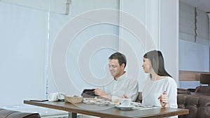 Happy couple paying bill brought by waiter and leaving cafe