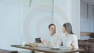 Happy couple paying bill brought by waiter and leaving cafe