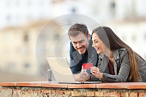 Happy couple paying online with credit card and laptop