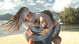 Happy couple, piggyback and playing in beach sun for bonding, love or support on holiday vacation. Man carrying woman on