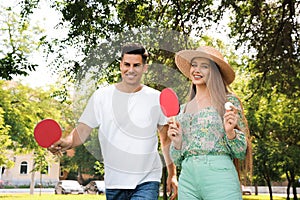 Happy couple with ping pong rackets and ball in park