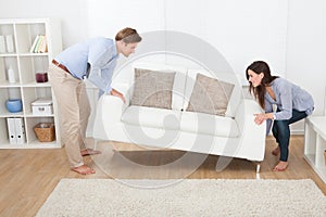Happy couple placing sofa in living room photo