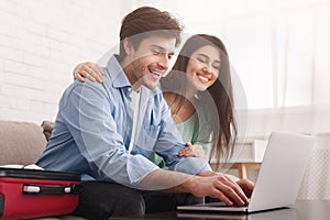 Happy couple planning travel, booking tickets online on laptop