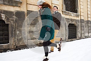 Happy couple playful together during winter holidays vacation outside in snow old center