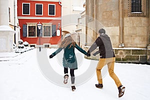 Happy couple playful together during winter holidays vacation outside in snow old center
