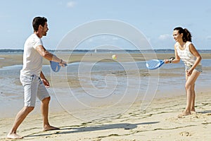 happy couple playing beach tennis