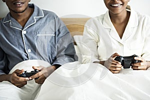 A happy couple playing video game in bed