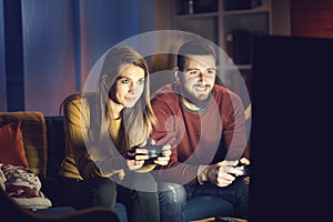 Happy couple playing video games together at home