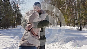 Happy couple playing winter game outdoors enjoying sunshine and warm winter weather in mountains. Man circles girl in his