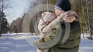 Happy couple playing winter game outdoors enjoying sunshine and warm winter weather in mountains.Man circles girl in his