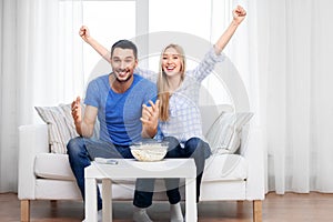 Happy couple with popcorn watching tv at home