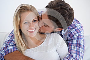 Happy couple, portrait and kissing with hug, marriage and embrace for love, home and couch. Wife, husband and smile for