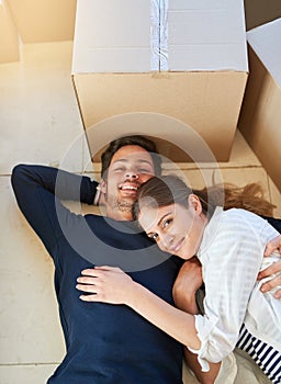 Happy couple, portrait and relax with box on floor for moving in new home, property or apartment above. Top view of man
