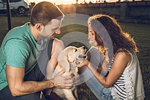 Happy couple with puppy dog in the country. Puppy breed Golden Retriever.Couple in a sunset with puppy dog