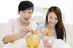 Happy couple putting coin into piggy bank