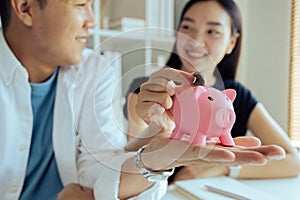 Happy couple putting coins in piggybank planning vacation or investments together