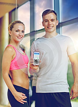happy couple with qr code on smartphone in gym