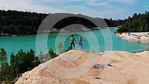 Happy couple raising their hands up - looking at a landscape of blue lake and green forest