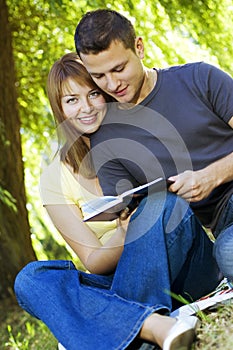 Happy couple reading a book outdoors