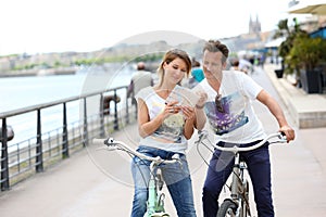 Happy couple reading map on bike tour in town