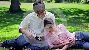Happy couple reading while sitting on the grass