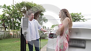 Happy couple recharge electric vehicle from EV charging station. Fastidious