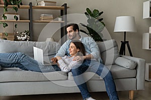 Happy couple relax on couch using modern laptop