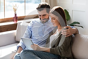 Happy couple relax on sofa using tablet gadget